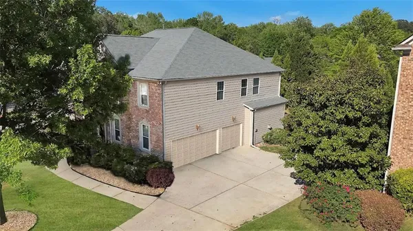 a aerial view of a house with yard and trees in the background