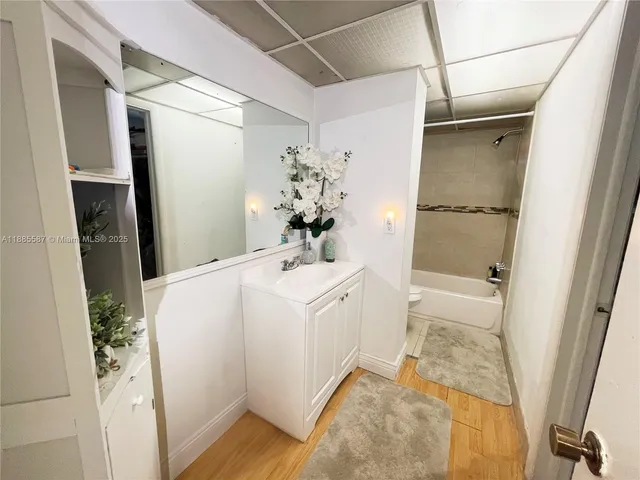 a bathroom with a sink and mirror with bathtub