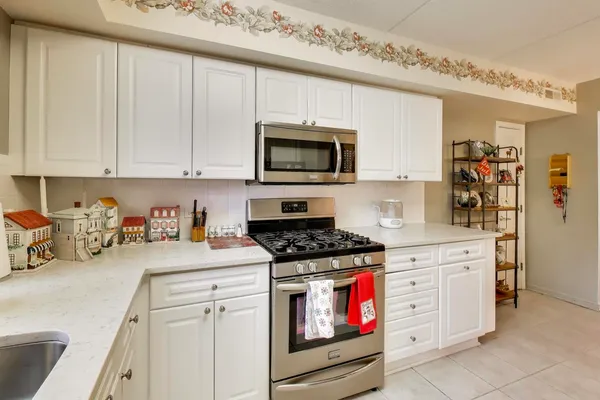 a kitchen with granite countertop white cabinets sink and stainless steel appliances