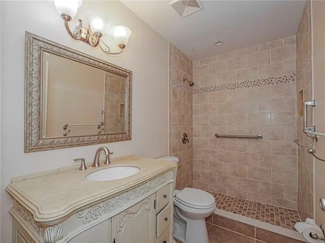 a bathroom with a granite countertop sink a toilet a mirror and shower