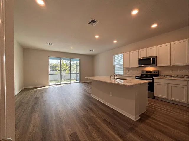 a kitchen with stainless steel appliances granite countertop a stove a sink dishwasher and a microwave oven with wooden floor