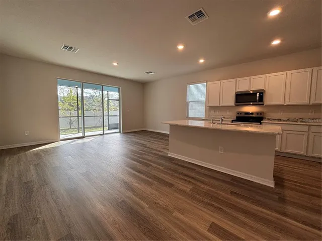 a view of kitchen with kitchen island wooden floor center island and stainless steel appliances