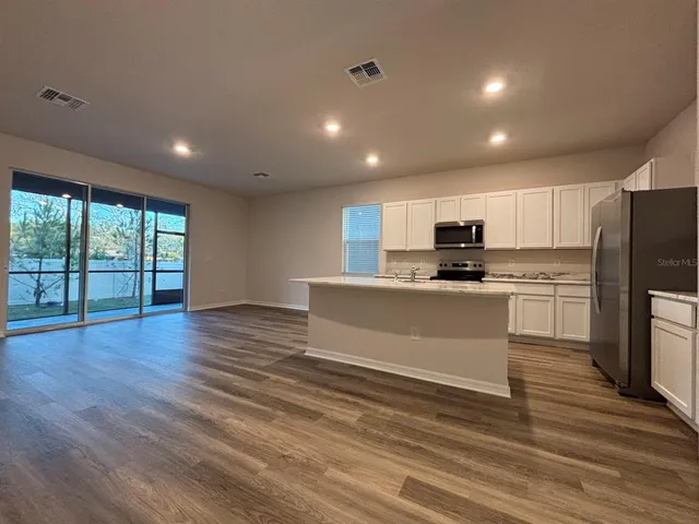 a large kitchen with kitchen island a sink wooden floor and stainless steel appliances