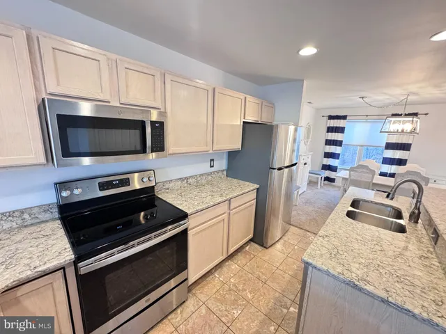 a kitchen with kitchen island granite countertop stainless steel appliances and wooden cabinets