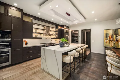 a kitchen with stainless steel appliances kitchen island granite countertop a table chairs sink and cabinets