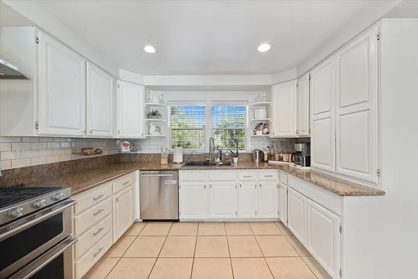 a kitchen with stainless steel appliances granite countertop a stove a sink and a microwave