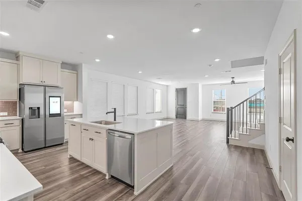 a kitchen with stainless steel appliances a sink dishwasher a refrigerator and wooden floor