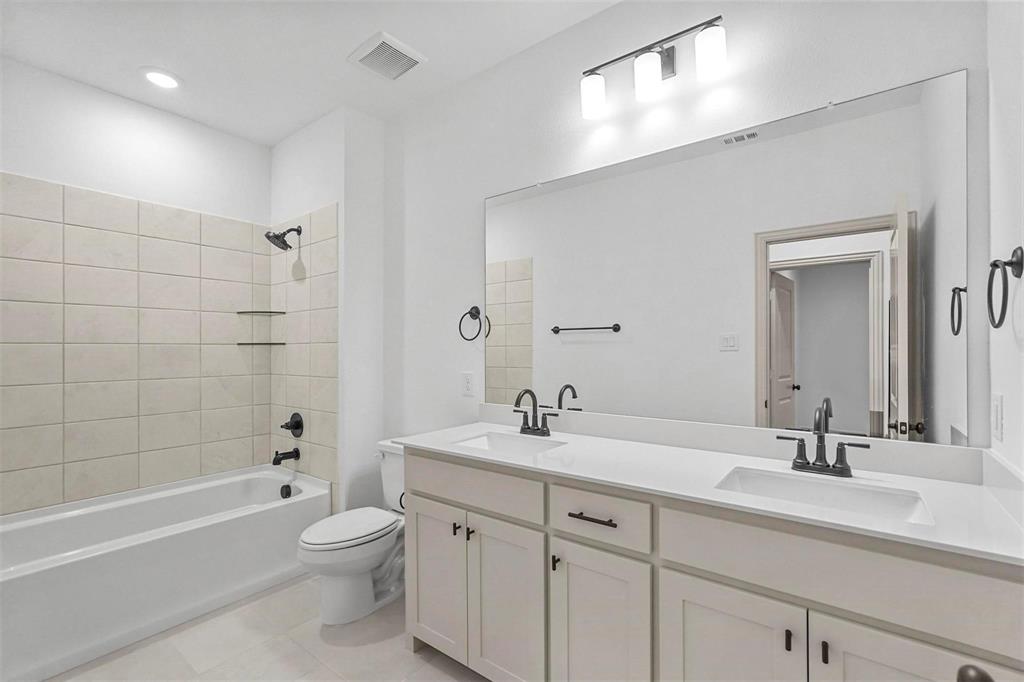 2640 Bluejack Road McKinney, TX 75071 - Photo 17 of 18 a bathroom with a double vanity sink toilet mirror and bathtub