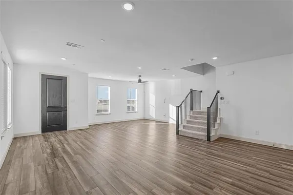 a view of empty room with wooden floor and kitchen