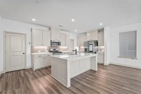 a kitchen with stainless steel appliances granite countertop a white cabinets and wooden floors