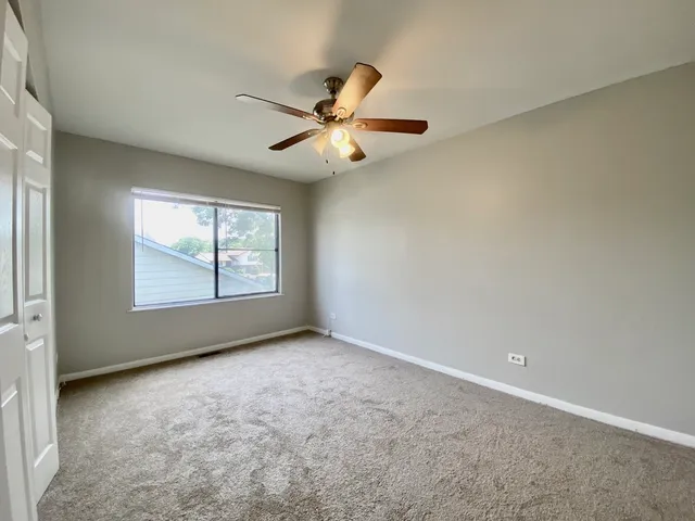an empty room with windows and fan