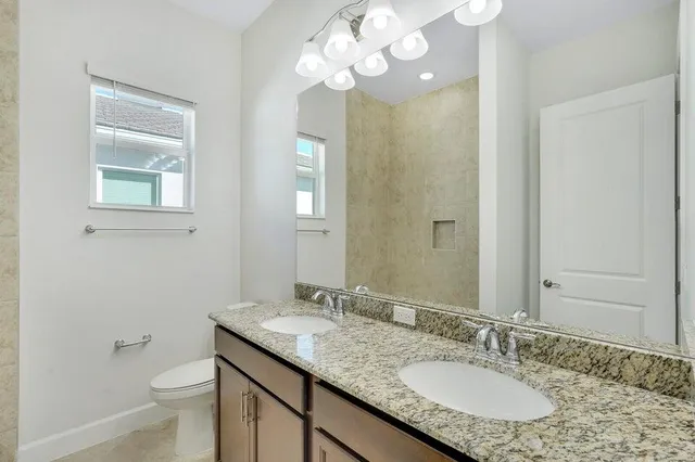 a bathroom with a granite countertop sink a toilet and a mirror