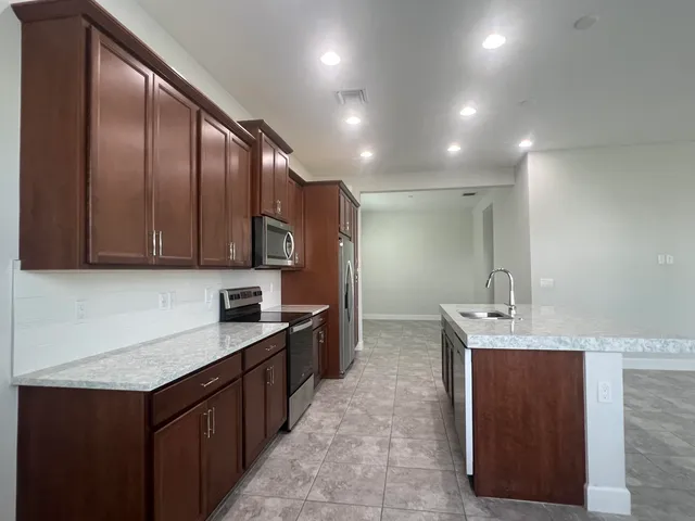 a kitchen with stainless steel appliances granite countertop a sink counter space cabinets and a large mirror
