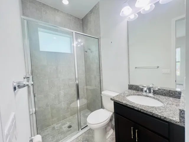 a bathroom with a granite countertop sink toilet and shower