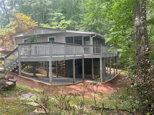 a view of house with backyard outdoor seating and covered with trees