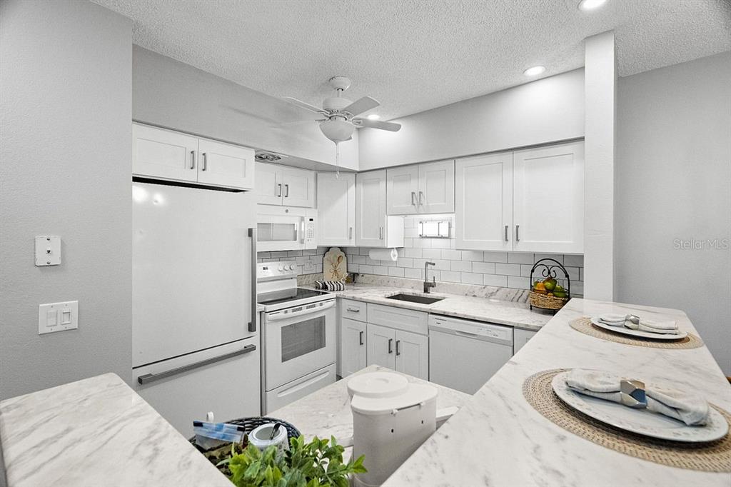 2391 Sumatran Way, Unit 69 Clearwater, FL 33763 - Photo 6 of 50 a kitchen with stainless steel appliances kitchen island granite countertop a sink a stove a dining table and chairs