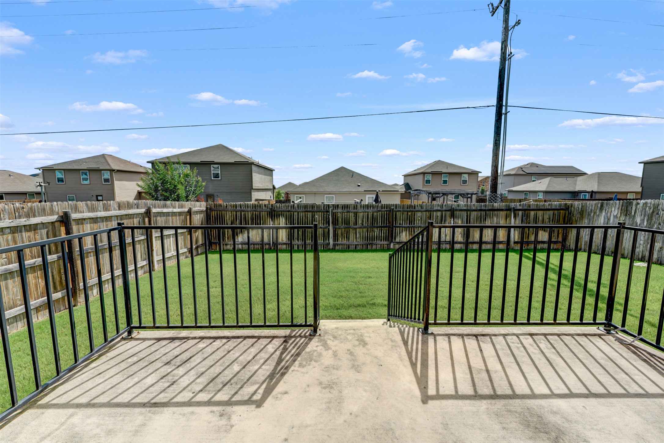 213 Ibis Falls Loop Jarrell, TX 76537 - Photo 28 of 37 A spacious backyard with a concrete patio, lush green lawn, and a secure privacy fence.