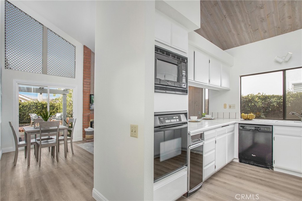 11 Ensueno West Irvine, CA 92620 - Photo 8 of 36 a kitchen with stainless steel appliances granite countertop a stove top oven a sink with white cabinets and wooden floor