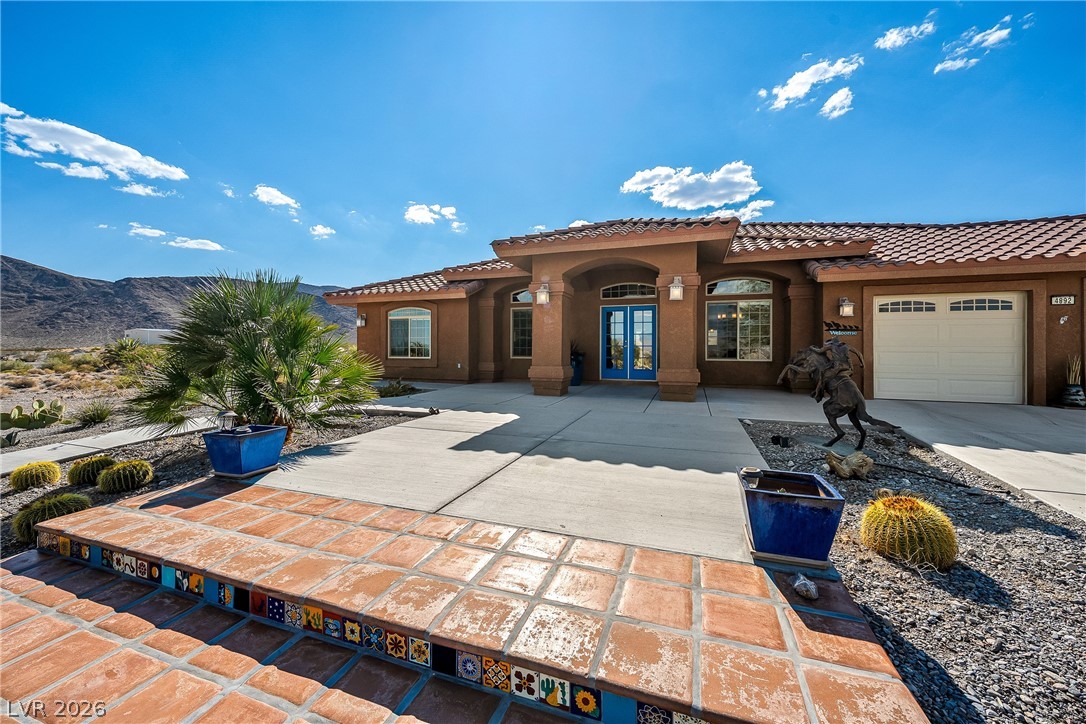 4892 Quail Run Road Pahrump, NV 89060 - Photo 4 of 90 This home features desert landscaping, a tiled entry, and a large garage, blending seamlessly with the natural surroundings.