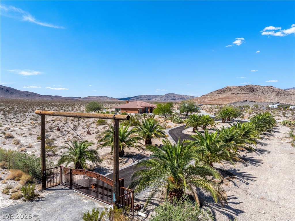 4892 Quail Run Road Pahrump, NV 89060 - Photo 8 of 90 This desert estate features a private gated entry and winding driveway leading to a secluded residence.