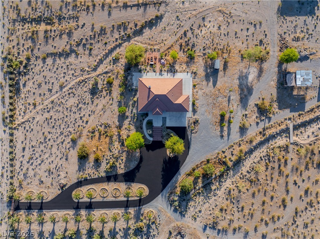4892 Quail Run Road Pahrump, NV 89060 - Photo 78 of 90 An aerial view showcases a desert property with a terracotta-roofed residence and winding driveway.