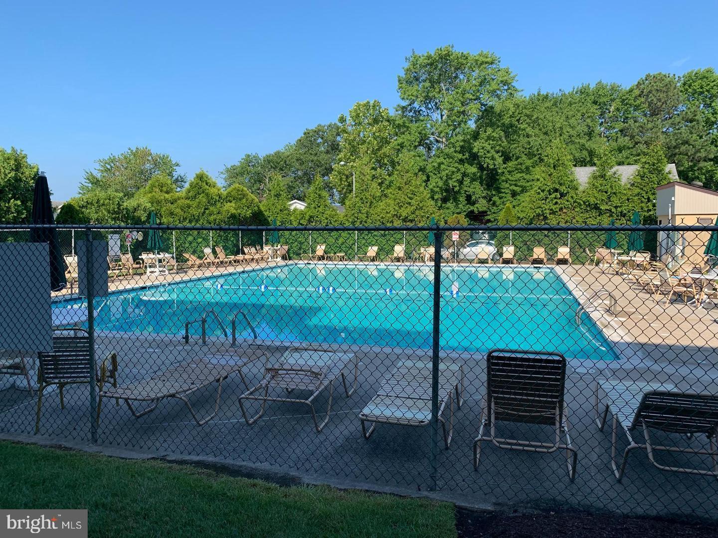 13908 North Ocean Road, Unit 8C Ocean City, MD 21842 - Photo 14 of 14 a view of a patio with lawn chairs floor to ceiling window and yard