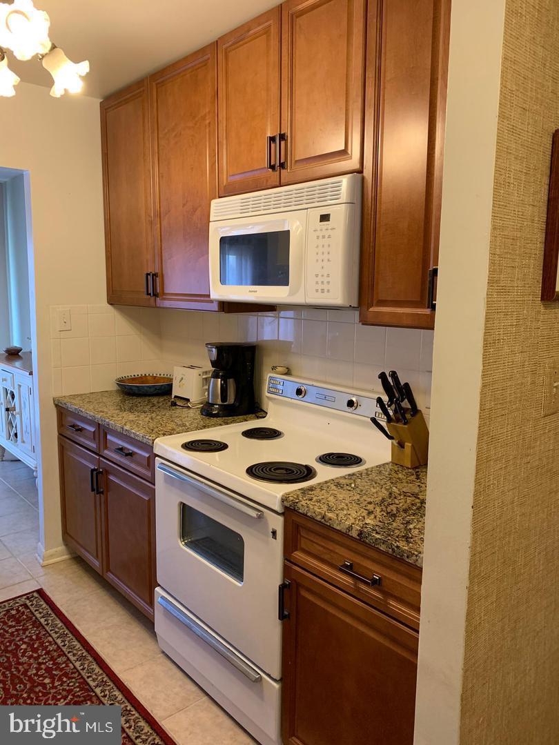 13908 North Ocean Road, Unit 8C Ocean City, MD 21842 - Photo 3 of 14 a kitchen with granite countertop a stove top oven a sink dishwasher and granite countertops with cabinets