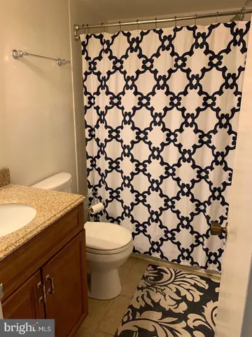 a bathroom with a granite countertop sink and a toilet