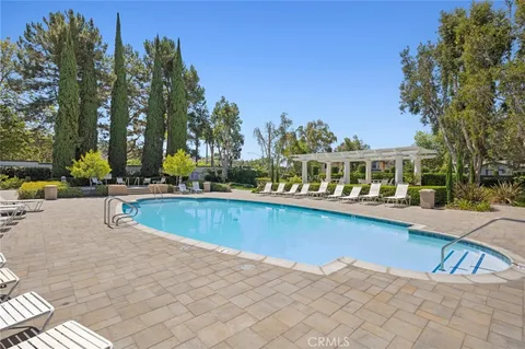 a view of swimming pool with outdoor seating and trees in the background