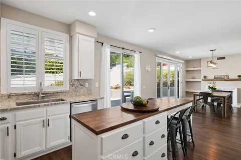 a kitchen with stainless steel appliances granite countertop a table chairs sink and wooden floor
