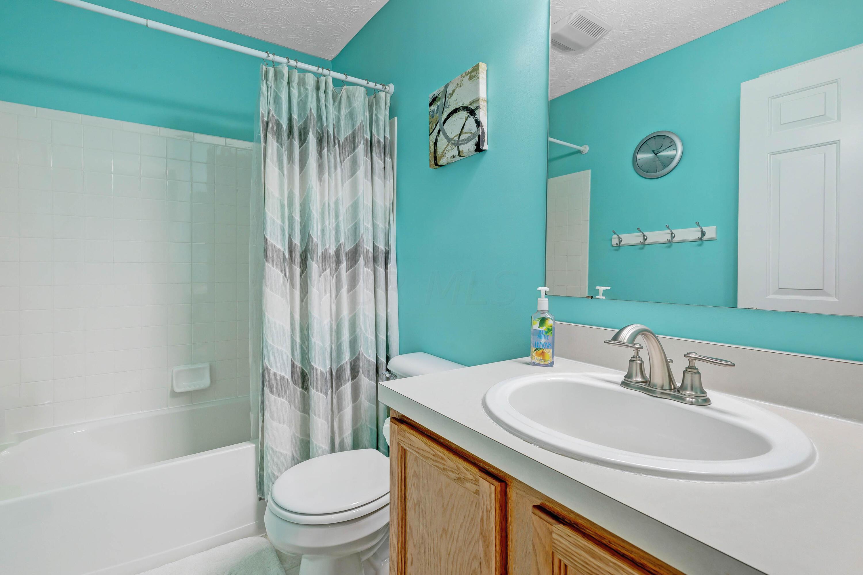 2136 Reeves Avenue Lewis Center, OH 43035 - Photo 38 of 57 • Neutral vinyl flooring • Green painted walls • Enclosed vanity with single bowl sinktop • 3 bulb wall light • Mirrored medicine cabinet • Tub/shower combination with ceramic tile surround • Lighted ceiling exhaust • Linen closet