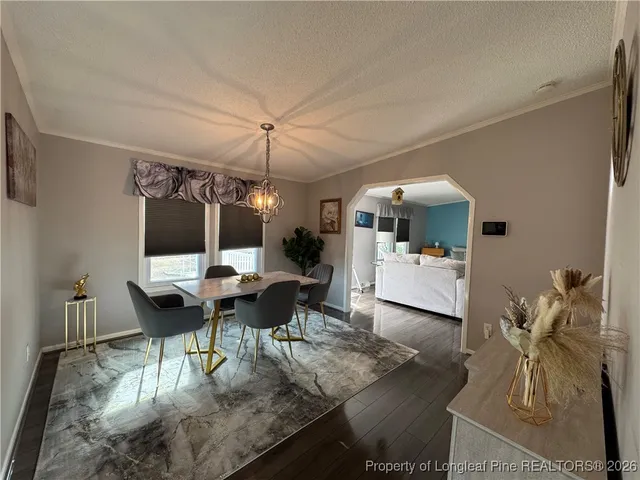 a living room with furniture a chandelier and a dining table with wooden floor