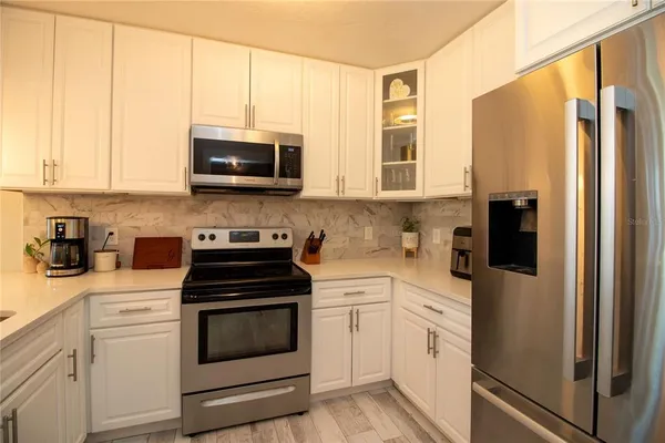 a kitchen with stainless steel appliances white cabinets and a stove top oven