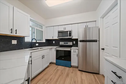 a kitchen with granite countertop a refrigerator and a stove top oven