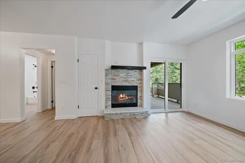 an empty room with wooden floor fireplace and windows