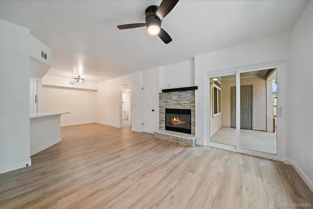 an empty room with wooden floor fireplace and windows