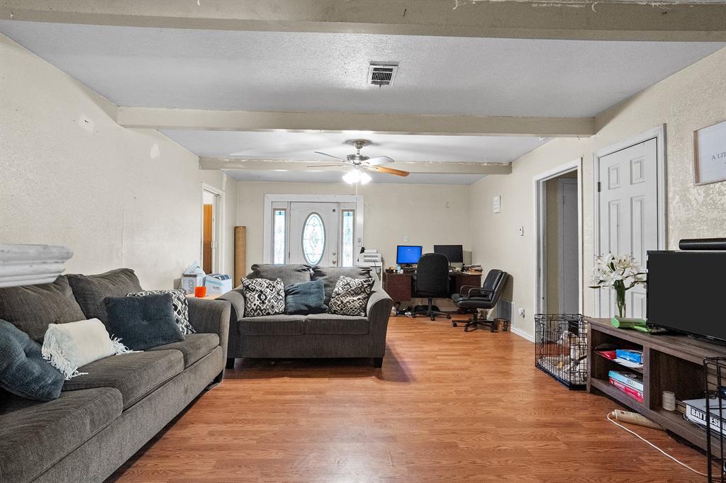 Living area with a desk, beam ceiling, light wood-style flooring, and a ceiling fan