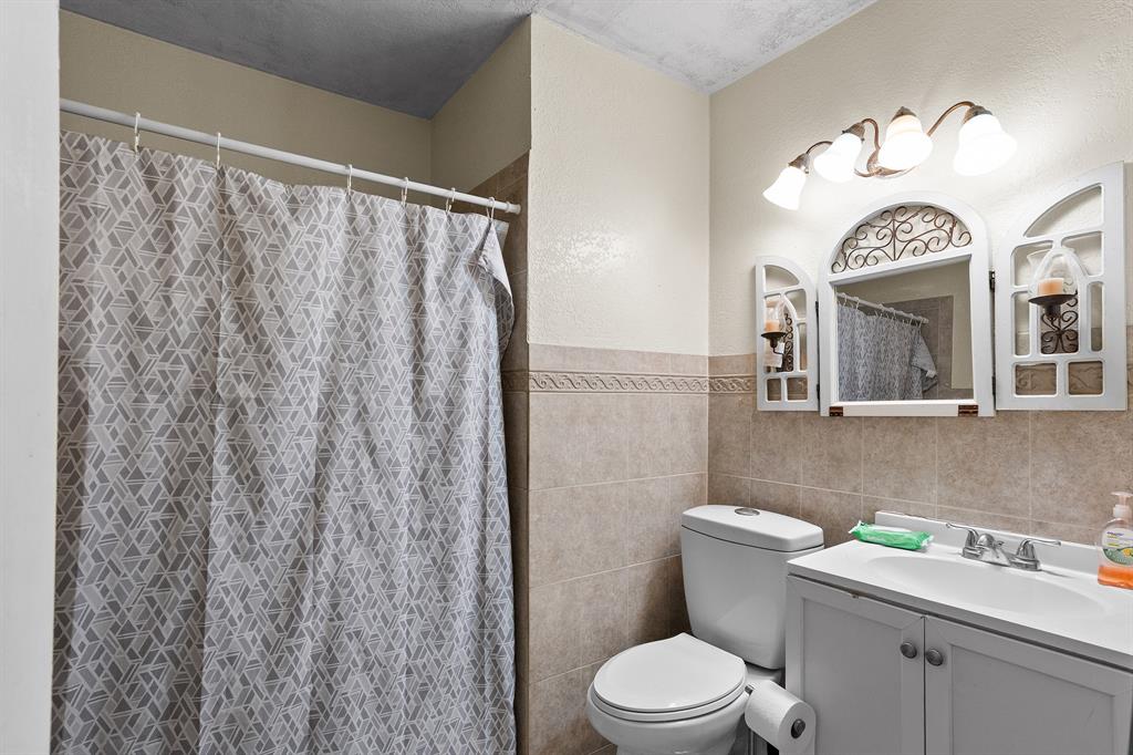 7826 Rilla Avenue Dallas, TX 75217 - Photo 9 of 10 Full bath featuring vanity, tile walls, and curtained shower