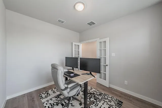 an empty room with wooden floor and windows