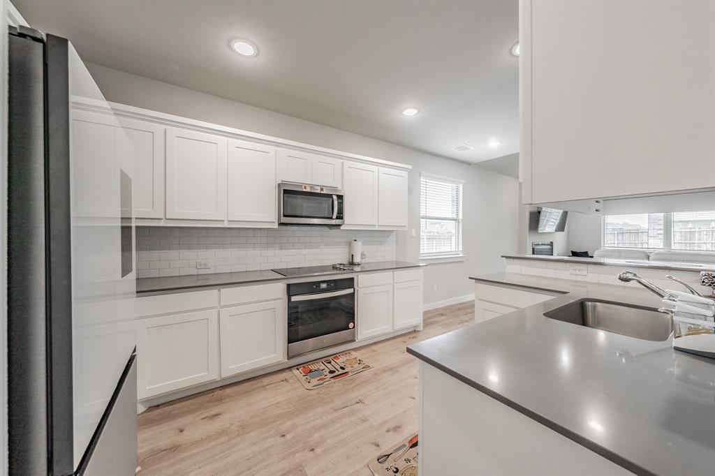 3202 Glorioso Drive Royse City, TX 75189 - Photo 21 of 40 a kitchen with kitchen island white cabinets appliances and a sink