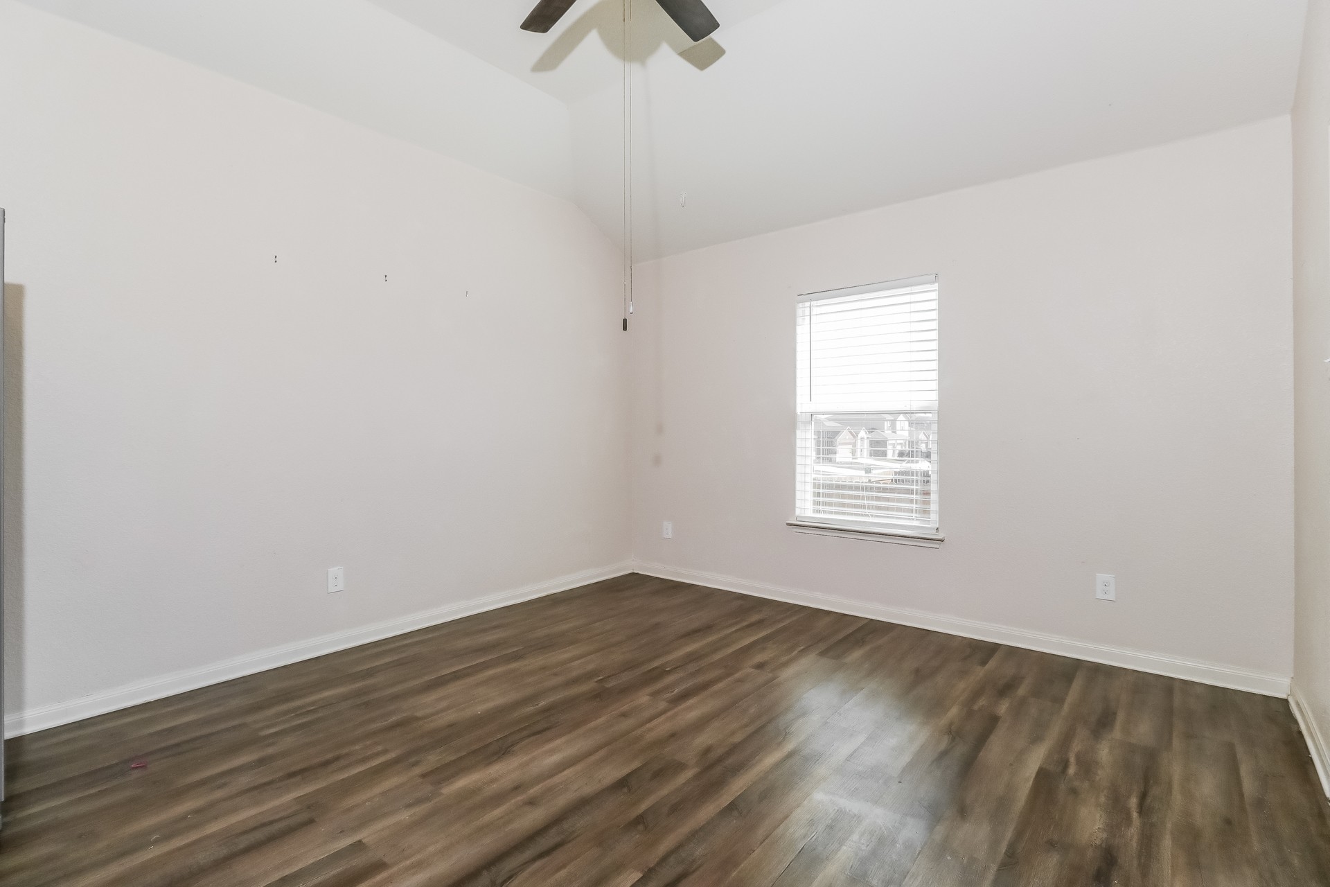20017 Hubert R Humphrey Road Manor, TX 78653 - Photo 4 of 27 A well-lit bedroom features durable hardwood flooring and a vaulted ceiling with a fan.