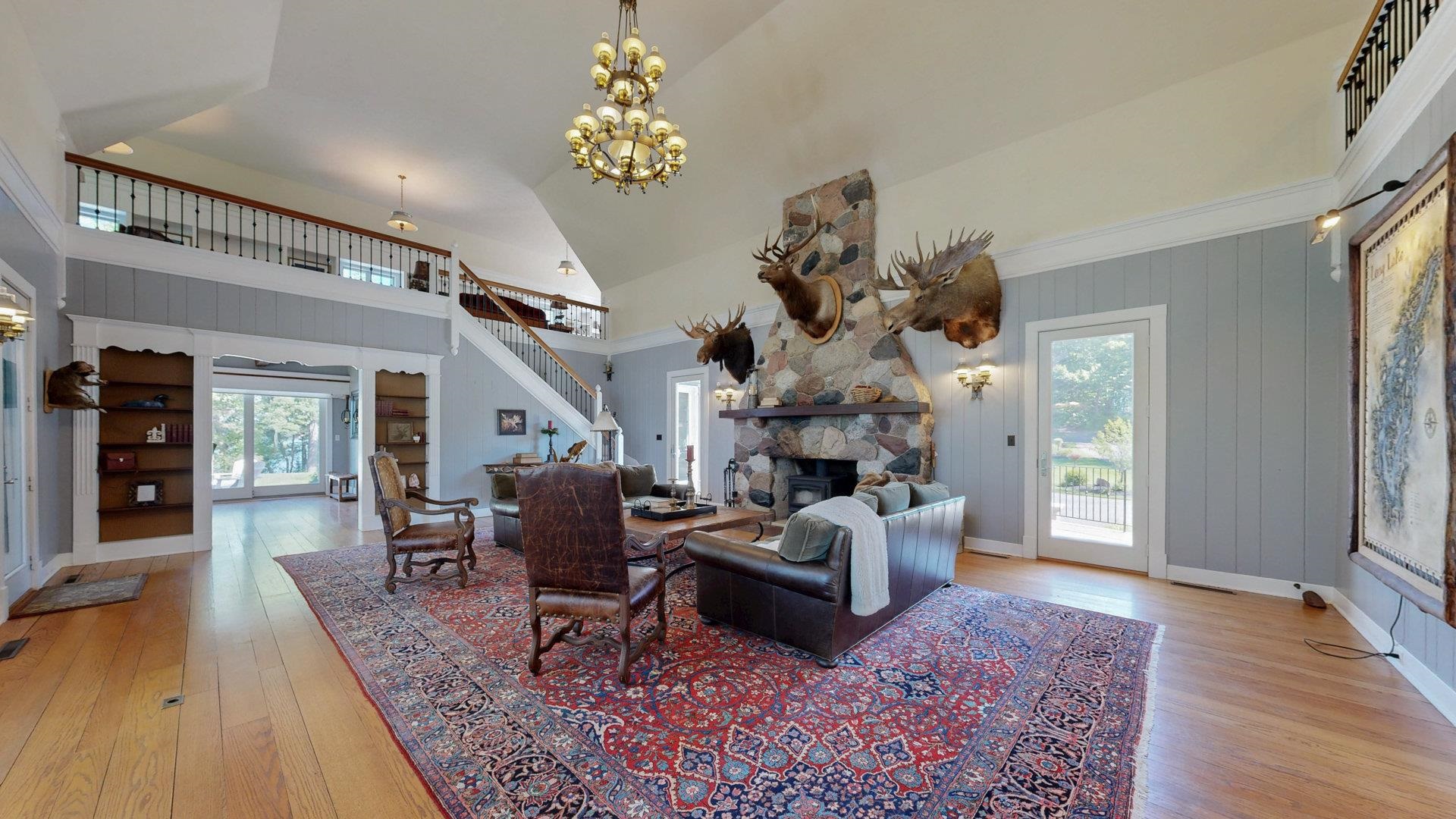 N1211 East Side Road Birchwood, WI 54817 - Photo 14 of 70 Living area featuring a fireplace, light wood-type flooring, stairway, high vaulted ceiling, and a chandelier
