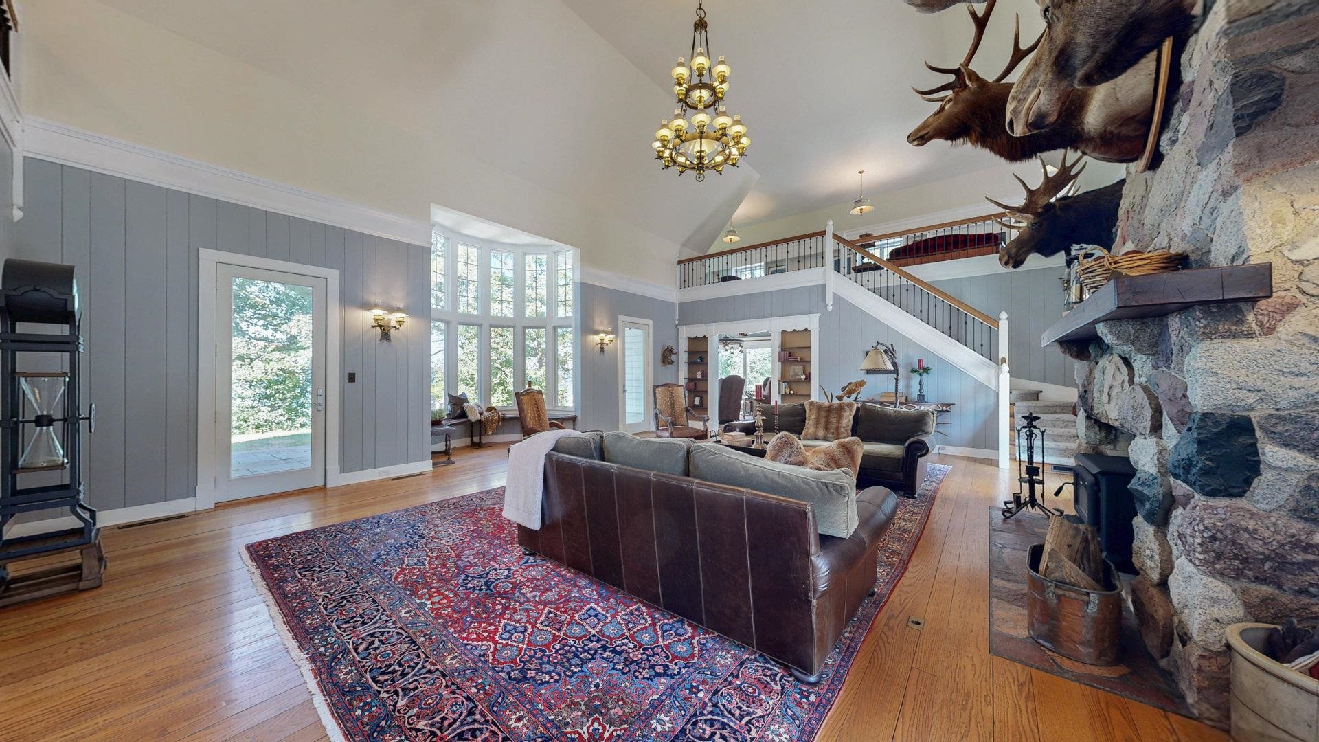 N1211 East Side Road Birchwood, WI 54817 - Photo 15 of 70 Living room featuring high vaulted ceiling, light wood-style flooring, a chandelier, stairway, and a fireplace