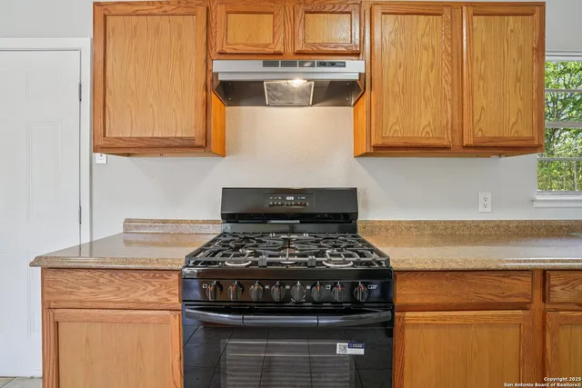 a kitchen with stainless steel appliances granite countertop white cabinets and a stove top oven
