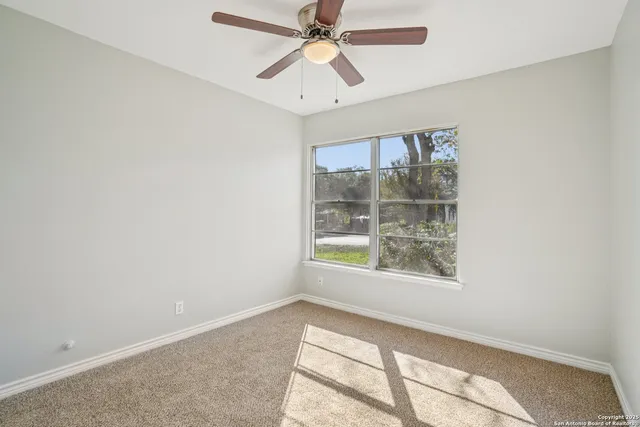 an empty room with windows and ceiling fan