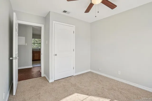 an empty room with a ceiling fan and carpet
