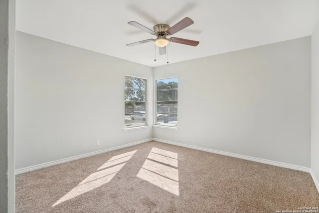 an empty room with windows and ceiling fan