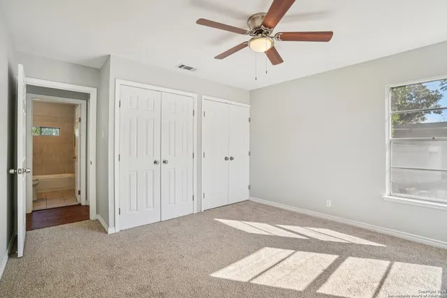 a view of empty room with window and ceiling fan