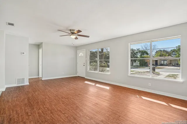 a view of an empty room with a window and wooden floor