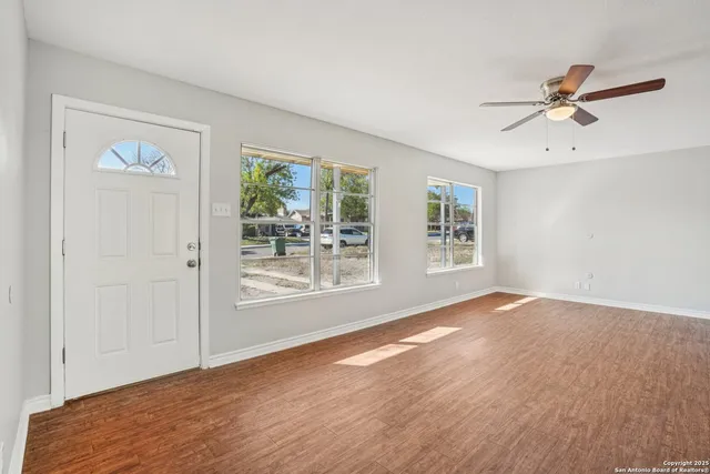 a view of an empty room with a window and wooden floor